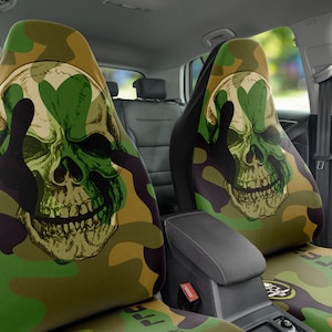 May include: Two car seat covers with a camouflage pattern featuring a green skull with a peace sign over its eyes.