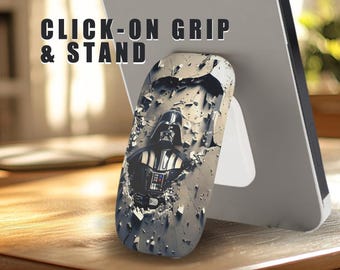 May include: A black and white phone grip with a Darth Vader image. The grip has a kickstand feature and says "CLICK-ON GRIP & STAND" in black text.