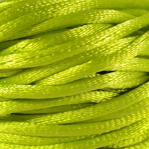 Può includere: Primo piano di un rotolo di nastro di raso verde brillante. Il nastro è morbido e lucido, ed è perfetto per l'artigianato, la decorazione o per aggiungere un tocco di eleganza a qualsiasi progetto.