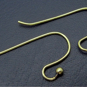 Peut inclure: Deux crochets d'oreille dorés avec une petite boule à l'extrémité de chaque crochet.