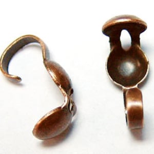 May include: Two antique copper-toned metal clasps with a rounded dome shape and a hook on one end. The clasps are used for jewelry making.