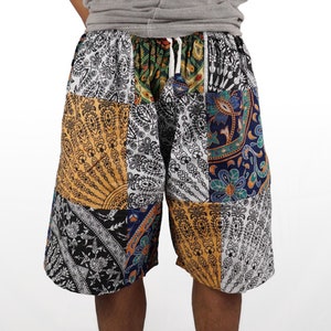 Könnte beinhalten: Patchwork-Shorts mit weißem Hintergrund und bunten Mustern in Blau-, Gelb- und Grüntönen. Die Shorts haben einen Kordelzug.