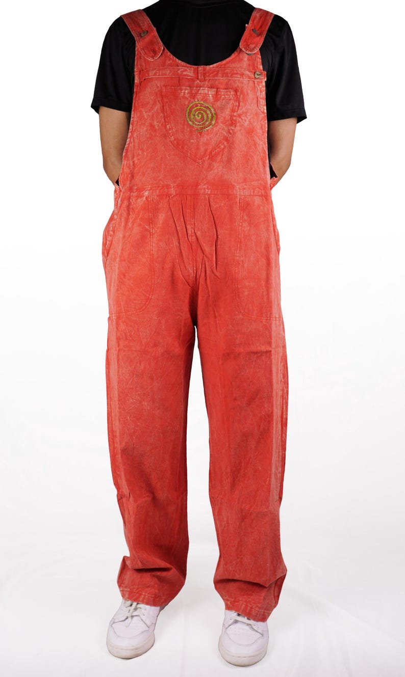 May include: Red denim overalls with a small embroidered design on the front pocket. The overalls have adjustable straps and a relaxed fit.