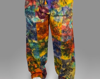 Puede incluir: Pantalones patchwork coloridos con cintura anudada. Los pantalones presentan una vibrante mezcla de colores que incluyen naranja, amarillo, azul y morado. Diseños florales negros están impresos en el patchwork. Los pantalones son holgados e informales.