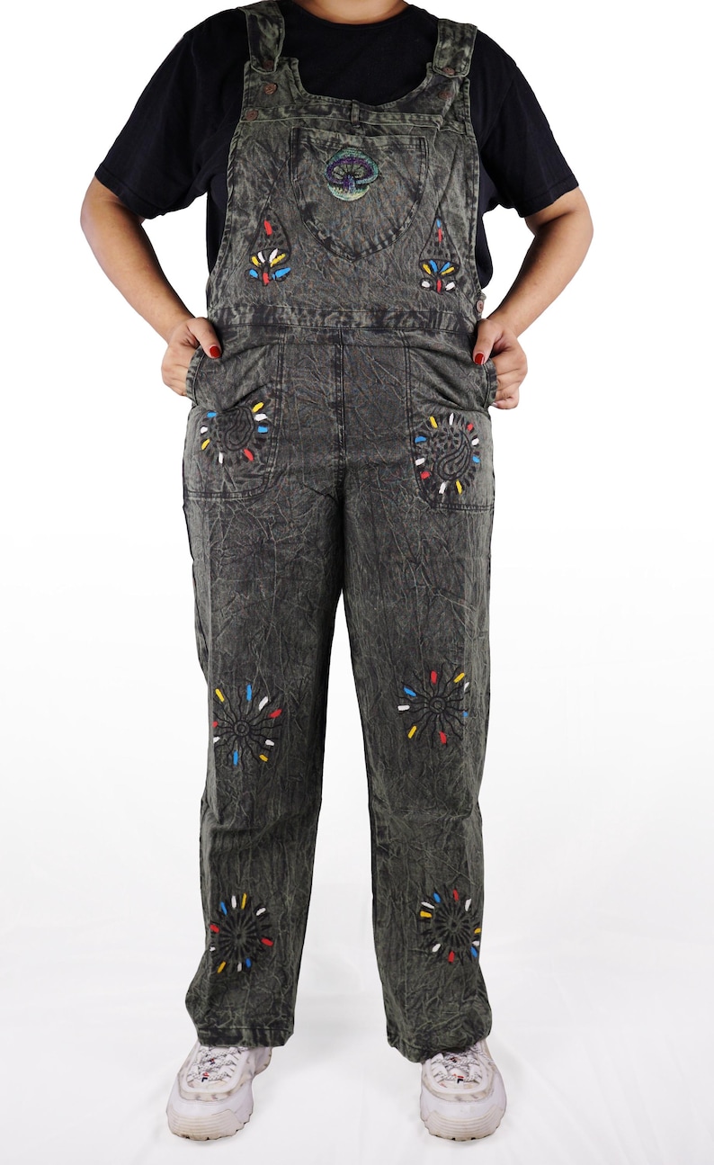 May include: Black denim overalls with colorful embroidered flowers and a mushroom design. The overalls have a relaxed fit and wide legs.