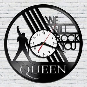May include: Black vinyl record clock featuring a silhouette of a person with the text "WE WILL ROCK YOU" and "QUEEN" below the clock face.