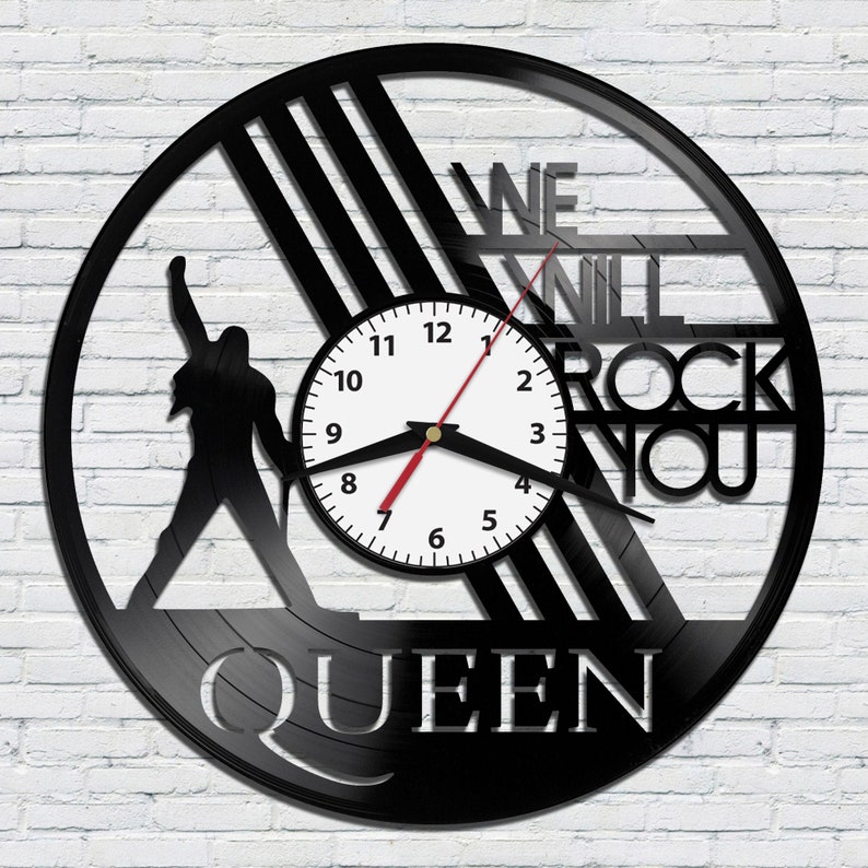 May include: Black vinyl record clock featuring a silhouette of a person with the text "WE WILL ROCK YOU" and "QUEEN" below the clock face.