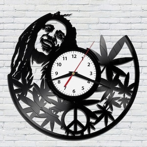 May include: Black vinyl record clock featuring a silhouette of Bob Marley with dreadlocks, marijuana leaves, and a peace sign. The clock face is white with black numbers and hands.