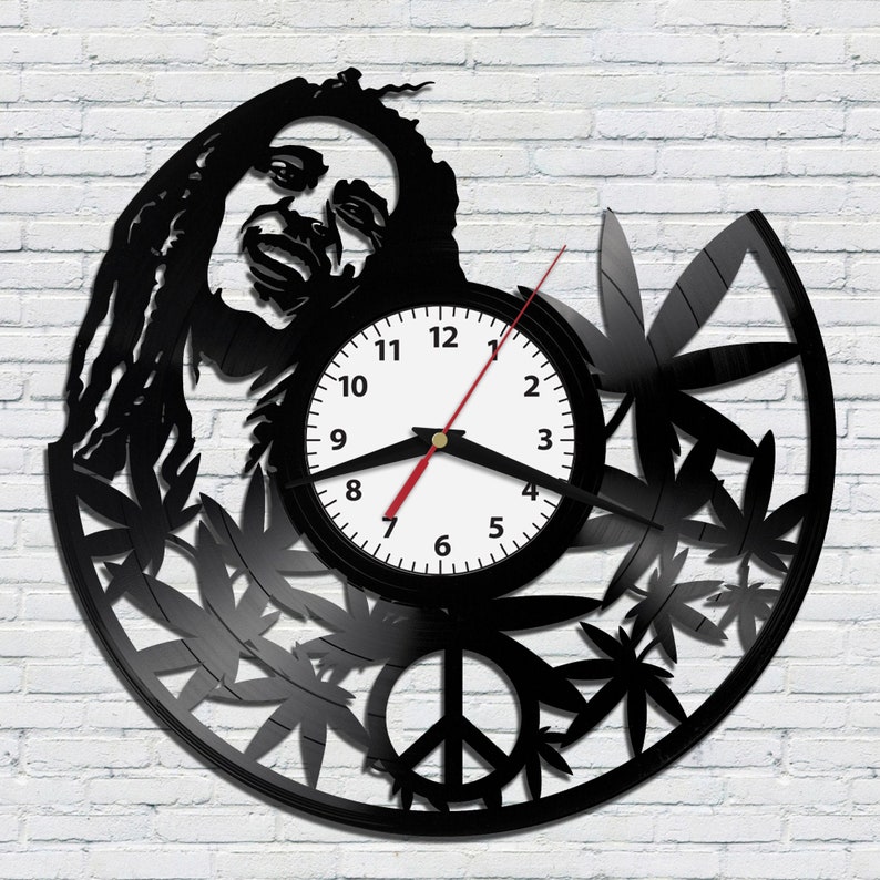 May include: Black vinyl record clock featuring a silhouette of Bob Marley with dreadlocks, marijuana leaves, and a peace sign. The clock face is white with black numbers and hands.
