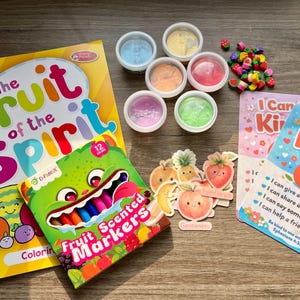 May include: A collection of children's educational materials, including a coloring book titled "The Fruit of the Spirit," a box of fruit-scented markers, colorful playdough, and cards with the text "I Can Be Kind!" and fruit illustrations.