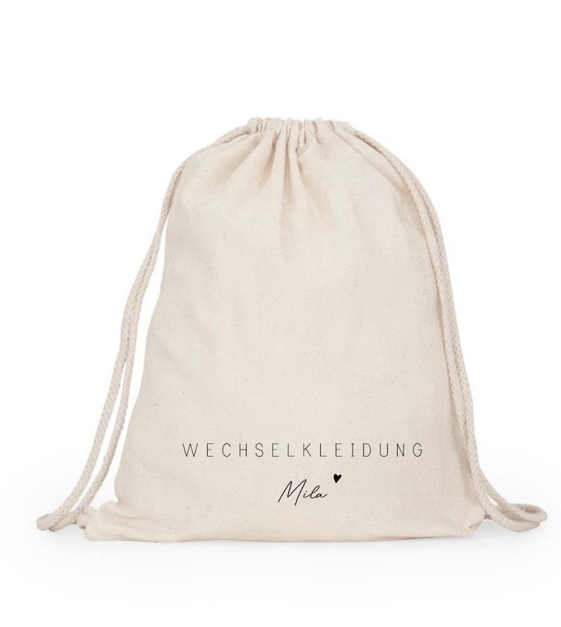 May include: A white drawstring bag with the text "WECHSELKLEIDUNG Mila" printed on it.