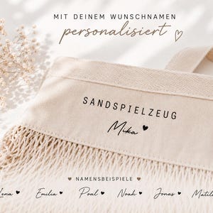 Puede incluir: Un bolso de mano de lona beige y malla con el texto impreso en negro SANDSPIELZEUG y el nombre Mika junto a un coraz&oacute;n. El bolso incluye un panel superior de lona resistente y una secci&oacute;n inferior de malla tejida con una correa a juego.