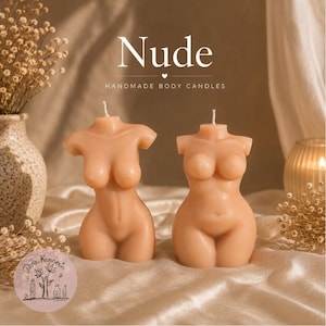 May include: Two light beige torso-shaped candles with a single wick at the top of each. The text Nude and HANDMADE BODY CANDLES is printed above the candles. The candles are smooth and feature a human-like form with defined chest and hip areas.