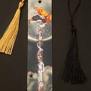 May include: A metal bookmark featuring an anime character with a sword, surrounded by lightning and a moon. The bookmark has a gold tassel and the text "鬼滅の刃" in Japanese.