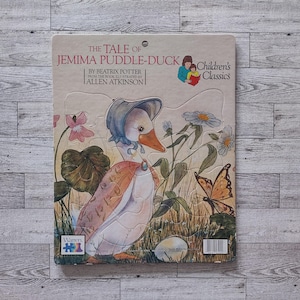 May include: A vintage children's puzzle featuring Jemima Puddle-Duck from Beatrix Potter's story. The puzzle shows a duck in a bonnet, a butterfly, and flowers. The puzzle is titled "The Tale of Jemima Puddle-Duck" and is part of the Children's Classics series.