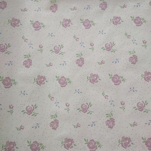 May include: A repeating pattern of pink roses, green leaves, and blue sprigs on a white background. Small gray dots are scattered throughout the design. The floral pattern is likely for wallpaper or fabric.