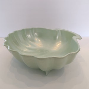 May include: A white ceramic mug with a black handle and the text "But First, Coffee" in a bold, black font. The mug is set against a neutral background, highlighting its simple design.