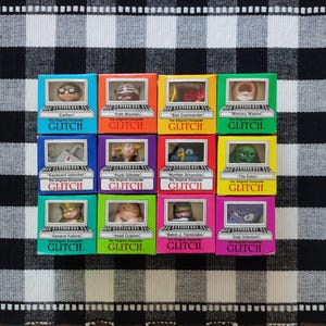 May include: Twelve colorful square boxes labeled GLITCH, each featuring a unique character inside a computer screen window. The boxes are arranged in a grid and include names like Carlton, Path Blocker, Bad Commander, Memory Masher, Keyboard Uplocker, Punk Glitcher, Number Scruncher, File Eater, General Failure, Head Crasher, Batch J. Terminator, and Disk Infectant.