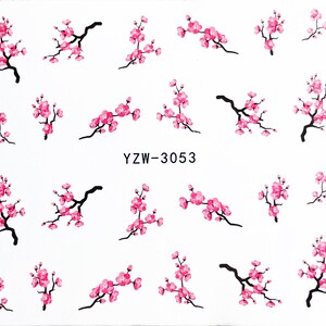 May include: A sheet of pink and black nail art stickers featuring cherry blossom designs. The sheet includes the text "YZW-3053".