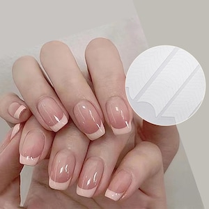 Pode incluir: Adesivos brancos para guiar as unhas para criar uma manicure francesa. Os adesivos são mostrados em uma mão com várias unhas pintadas com uma ponta branca.