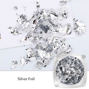 May include: A clear jar filled with silver foil flakes. The foil is scattered around the jar on a white surface. The text "Silver Foil" is printed below the jar.