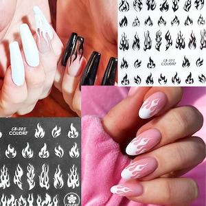 May include: Two sheets of nail art stickers with a flame design. One sheet has black flames on a white background and the other sheet has white flames on a black background. The text "CB-205 COLORF" is printed on both sheets.