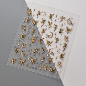 May include: A sheet of clear nail stickers with gold fairy and crescent moon designs. The sheet also includes small gold stars and rhinestones.