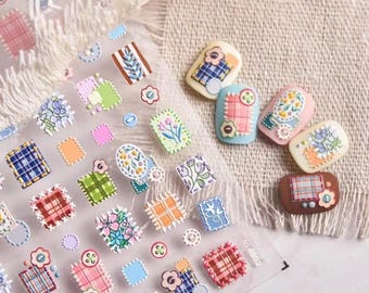 May include: A sheet of colorful nail stickers with a patchwork design. The stickers feature various patterns, including plaid, floral, and geometric designs. The stickers are arranged in a grid pattern on a clear sheet.