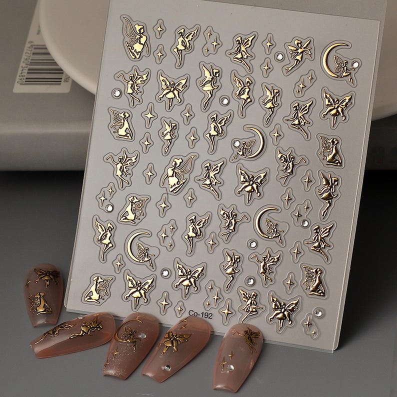 May include: A sheet of gold nail art stickers with a design of fairies, stars, and moons. The sheet is labeled "Co-192".