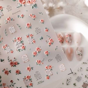Puede incluir: Pegatinas transparentes para decoraci&oacute;n de u&ntilde;as con un dise&ntilde;o floral de rosas, las palabras "Love Rose" y texto escrito. Las pegatinas tienen un efecto 3D y son en tonos rojos, rosas y verdes. La imagen tambi&eacute;n muestra u&ntilde;as manicuradas con dise&ntilde;os florales similares.