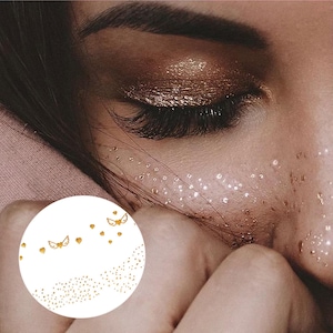 Peut inclure: Tatouage temporaire doré avec une dispersion de petits points et quelques points plus grands avec des ailes. Le tatouage est conçu pour ressembler à des taches de rousseur.