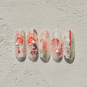 K&ouml;nnte beinhalten: F&uuml;nf ovale Nageldesigns mit wei&szlig;em Hintergrund und roten, schwarzen und gr&uuml;nen Akzenten. Die Designs zeigen japanische Schriftzeichen, Blumen und Bambus.