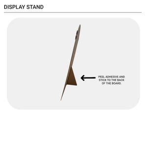 May include: A brown triangular display stand shown in profile, attached to a flat board. Text at the top reads DISPLAY STAND. An arrow points to the stand with the text: PEEL ADHESIVE AND STICK TO THE BACK OF THE BOARD.