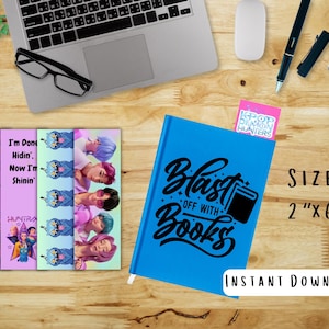 May include: A blue notebook with the text "Blast off with Books" and a black book graphic. Several colorful bookmarks with images of people and text are next to the notebook. The bookmarks are 2" x 6".
