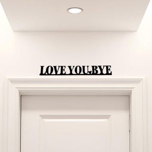 Puede incluir: Una puerta blanca con un letrero negro encima que dice "LOVE YOU, BYE".