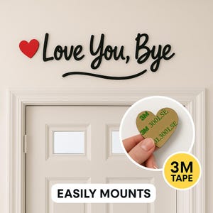 May include: Black wooden wall art with the phrase "Love You, Bye" and a red heart. The words are above a door with the text "EASILY MOUNTS" below. A heart-shaped adhesive pad is shown with the text "3M TAPE".