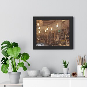 Peut inclure: Une photographie encadrée d'une pièce avec un plafond haut et de nombreuses lumières suspendues. La pièce est remplie de divers objets, y compris des outils, des meubles et d'autres articles. Les murs sont de couleur brun clair et le sol est de couleur brun foncé.