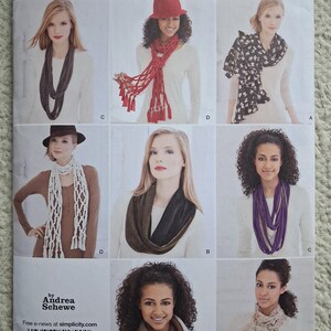 May include: Simplicity sewing pattern featuring various scarf designs. The image showcases different styles, including a dark gray infinity scarf, a red fringed scarf, and a black and white patterned scarf. The pattern includes the text "1790" and "by Andrea Schewe".