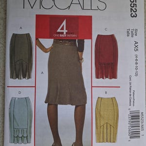May include: A McCall's M5523 sewing pattern envelope featuring four skirt designs labeled A, B, C, and D. The cover displays a brown skirt, with illustrations of olive, red, yellow, and light blue skirt variations. The text includes size AX5 (4-6-8-10-12).