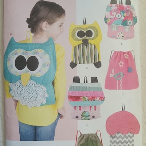 May include: A sewing pattern for making five different children's backpacks. The patterns include an owl, a house, a bird, a mushroom, and a tree. The pattern is from Simplicity and is called "The Villa Loft".