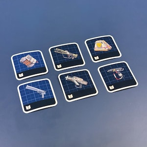 May include: Six square game cards with illustrations of futuristic weapons. Each card has a blue grid background and a white border. The weapons include a pistol, a rifle, and a grenade.