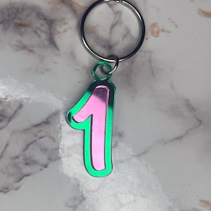 May include: A pink and green metal keychain with the number "1" on it.