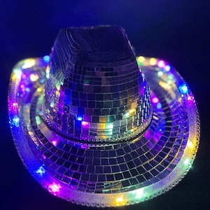 May include: A silver disco ball cowboy hat with multi-colored LED lights around the brim.