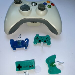 May include: A white Xbox 360 controller with four different colored plastic game controller keychains. The keychains are blue, green, and two shades of green.