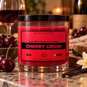 May include: A 9oz soy blend candle in a clear glass jar with a black lid. The red label reads Cherry Crush, Black Cherry, Red Wine, Oak and Vanilla, 9oz, 60H, and the happy candle with a smiley face and flame icon.