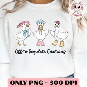 May include: White sweatshirt featuring three cartoon geese wearing hats and boots. The geese are decorated with bows and flowers. The text "Off to Regulate Emotions" is printed below the geese.