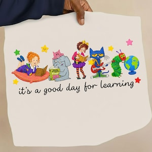 Puede incluir: Una tela de color claro con una ilustración colorida de personajes de libros infantiles leyendo y tocando música, con el texto "it's a good day for learning" en letra cursiva negra. El diseño incluye estrellas, un globo terráqueo y una oruga.