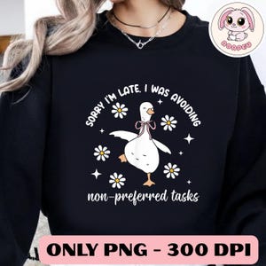 May include: Black sweatshirt with a white cartoon goose wearing a pink bow tie, surrounded by daisies and stars. Text reads "SORRY I'M LATE. I WAS AVOIDING non-preferred tasks." A pink and white logo is in the upper right corner.