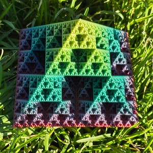 May include: A colorful 3D printed model of the Sierpinski triangle, a fractal geometric shape. The model is made of plastic and has a gradient of colors from red to green.