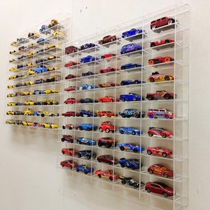 May include: A clear acrylic display case filled with a collection of miniature toy cars. The cars are arranged in rows on shelves and are in various colours, including red, blue, yellow, and black.